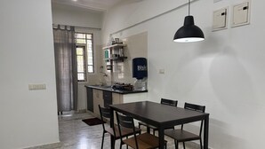 A dining area with a table and chairs, a kitchen area with a sink and cabinets, and a pendant light.