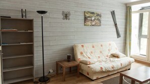 A living room with a sofa, a coffee table, a floor lamp, a bookshelf, and a window with curtains.
