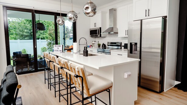 A modern kitchen with a central island, stainless steel appliances, and a view to the outside.