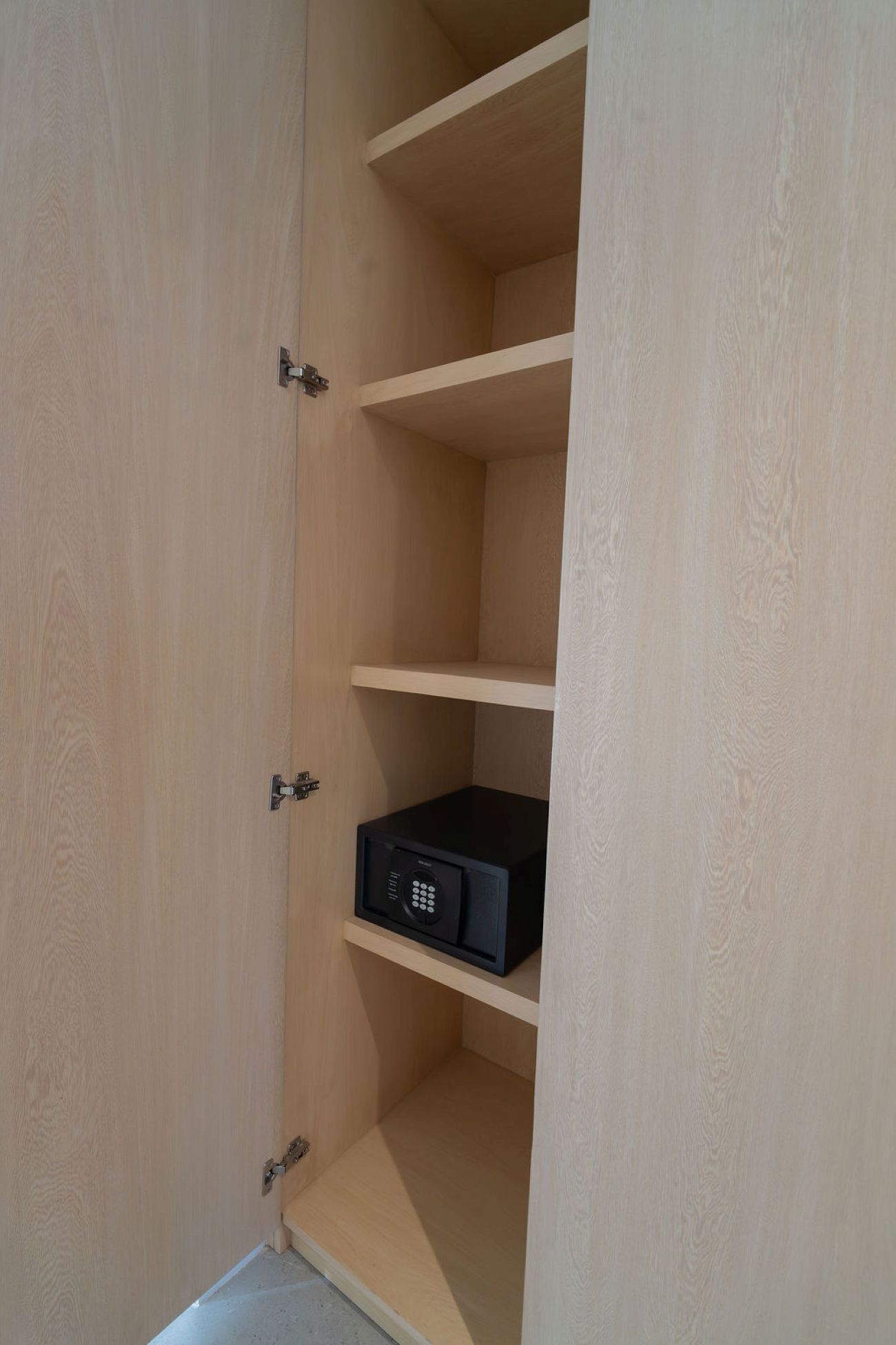 Un meuble en bois avec trois étagères, et un appareil électronique noir placé sur l’étagère du milieu.