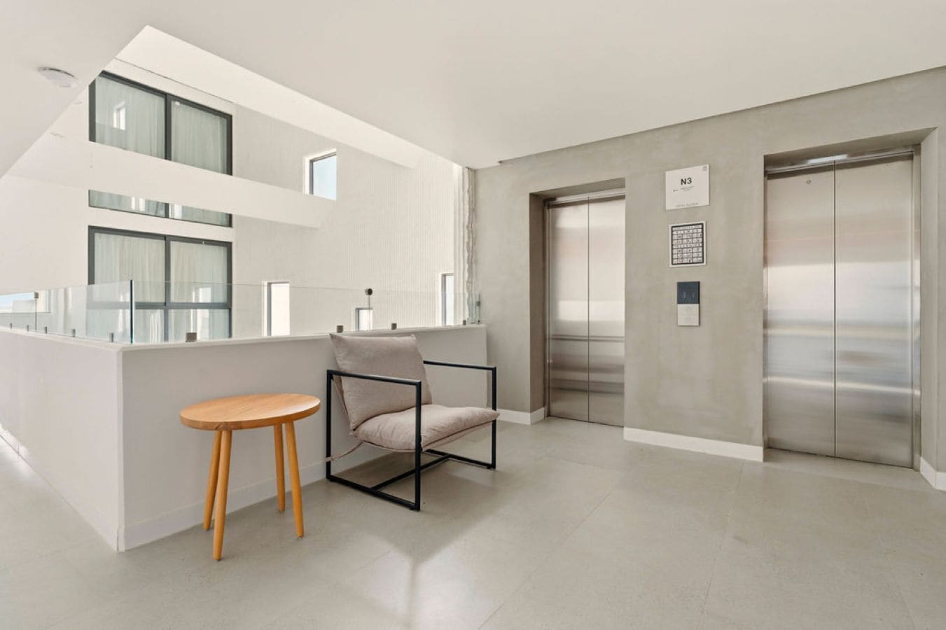 A modern interior with a kitchen area, a dining table, a chair, and an elevator.