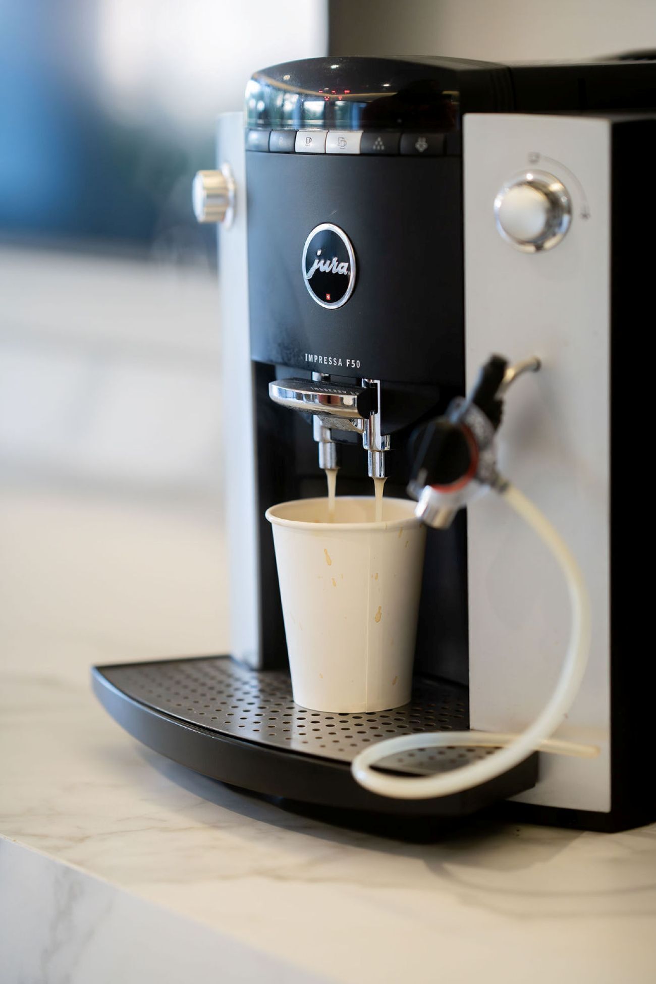 A Jura coffee machine dispensing coffee into a disposable cup.
