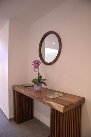 A wooden reception desk with a potted orchid and a magazine. - Hotel Alcalà Centro (Guadalajara)