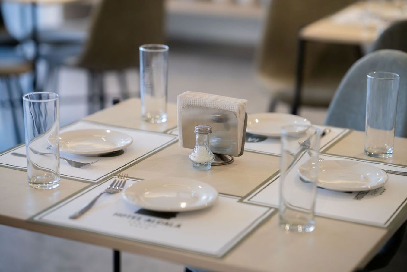 A neatly set dining table with plates, cutlery, and glasses.