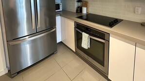 A modern kitchen with stainless steel appliances, white cabinets, and a tiled backsplash.