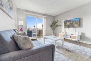 A modern living room with a grey sofa, a white coffee table, and a flat-screen TV mounted on the wall. - Pool -Gym- Great for Mid/Long Stays (Mesa)