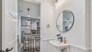 A modern kitchen with white cabinets, a bar stool area, and a pendant light. - Modern Ybor City Townhouse with Rooftop Views (Tampa)