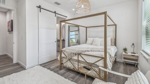 A modern bedroom with a four-poster bed, a small bedside table, and a hanging light fixture. - Modern Ybor City Townhouse with Rooftop Views (Tampa)
