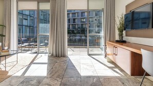 Ein modernes Wohnzimmer mit einem großen Schiebeglastür, die auf einen Balkon führt, einem Wand-Fernseher und einem Holzschrank.