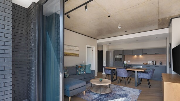 A modern living space with a sofa, round coffee table, and dining area. - Cosy and Charming Bridgewater One Apartment | Wifi (Cape Town)