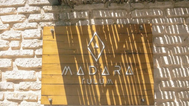 Ein Schild mit der Aufschrift 'MADARA RUM', das an einer Backsteinmauer befestigt ist.