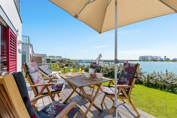 A deck with outdoor seating, a table, and a large umbrella.