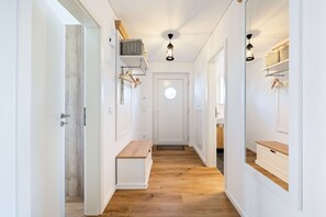 A hallway with wooden flooring, white walls, and a round mirror on the wall.