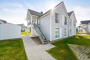 A residential building with a covered porch, a staircase, and a paved walkway.