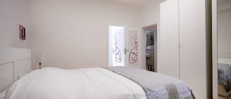 Un dormitorio con cama, armario y puerta con un póster.