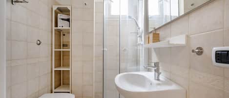 A bathroom with a toilet, a glass shower enclosure, a sink, and a mirror.