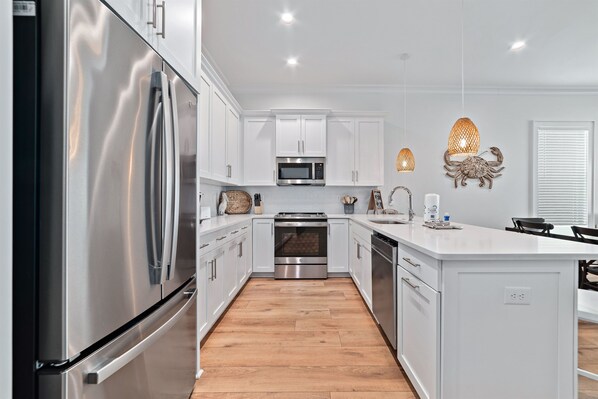 A modern kitchen with stainless steel appliances, white cabinetry, and a central island.