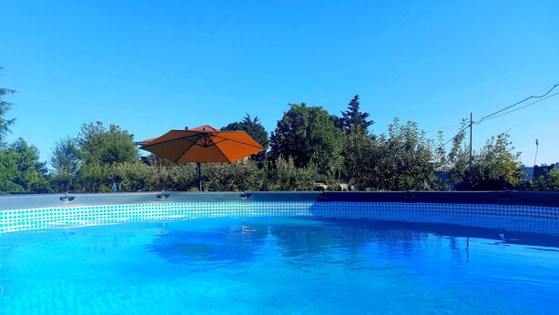A clear blue swimming pool with a tiled edge, surrounded by trees and an umbrella. - 15 minutes from Turin. Matilda House (Piemonte)