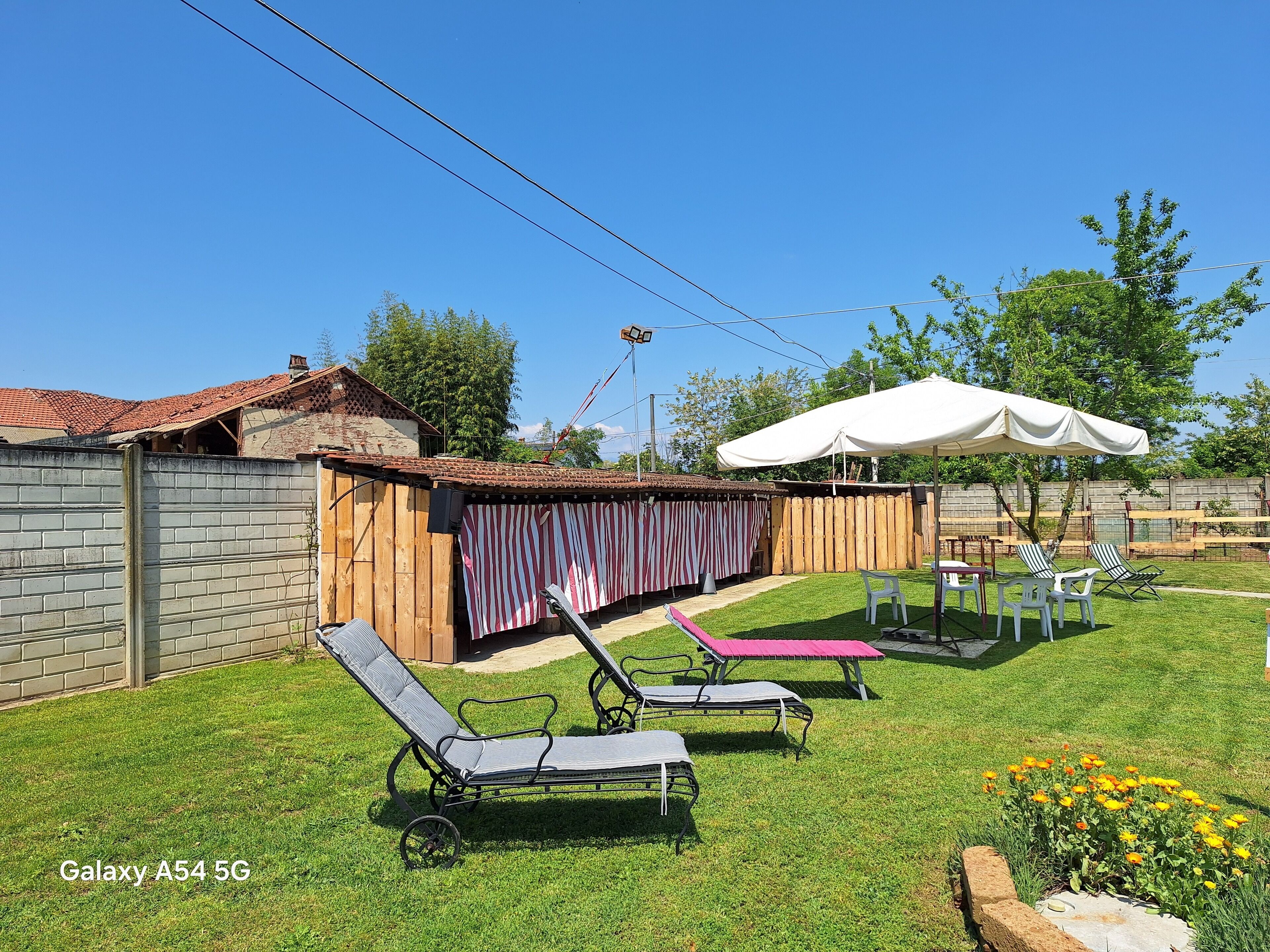 A backyard with a brick wall, a wooden fence, and a patio area with lounge chairs and a table.