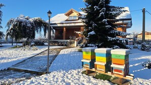 A snow-covered landscape with a wooden house, a stone structure, and colorful beehive stands. - 15 minutes from Turin. Matilda House (Piemonte)