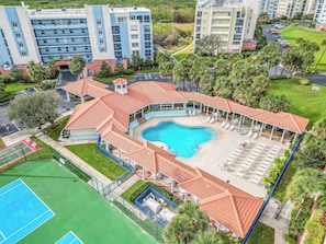 A resort with a swimming pool, sun loungers, and a tennis court.