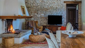 A cozy living room with a stone wall, a fireplace, a television, and comfortable seating. - Foresteria Casaforte Bergum at the gates of Cividale (Friuli-Venezia Giulia)