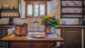 A rustic kitchen with a wooden table, a copper pot, wine glasses, and a vase of flowers. - Foresteria Casaforte Bergum at the gates of Cividale (Friuli-Venezia Giulia)