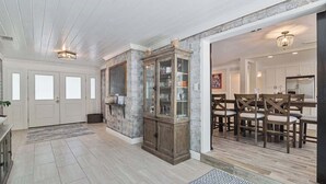 A spacious living area with a large wooden cabinet, a dining table with chairs, and a kitchen visible through an open doorway. - Gator Shack, Luxury Chic! (Gainesville)