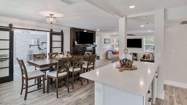 A modern kitchen with a dining area, a large island, and a built-in TV. - Gator Shack, Luxury Chic! (Gainesville)