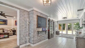 A spacious living area with a fireplace, a large window, and a ceiling fan. - Gator Shack, Luxury Chic! (Gainesville)