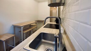 Une petite cuisine équipée d’un évier, d’une cuisinière et d’un plan de travail. On y trouve également des tabourets et une table dans un coin.