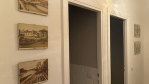 Un couloir avec quatre photographies historiques encadrées accrochées au mur, une porte blanche et un mur en briques blanches.