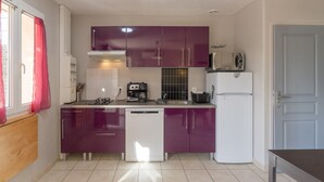 A compact kitchen with purple cabinets, a white dishwasher, a white refrigerator, and a microwave on the countertop. - Holiday Home 'Chêne' with Mountain View, Wi-Fi and Air Conditioning (Les Vans)