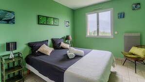 Une pièce avec un lit, une chaise, une lampe et une fenêtre.