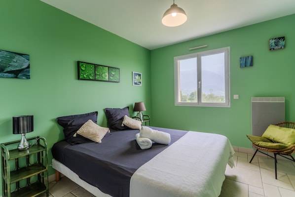 A room with a bed, a chair, a lamp, and a window.
