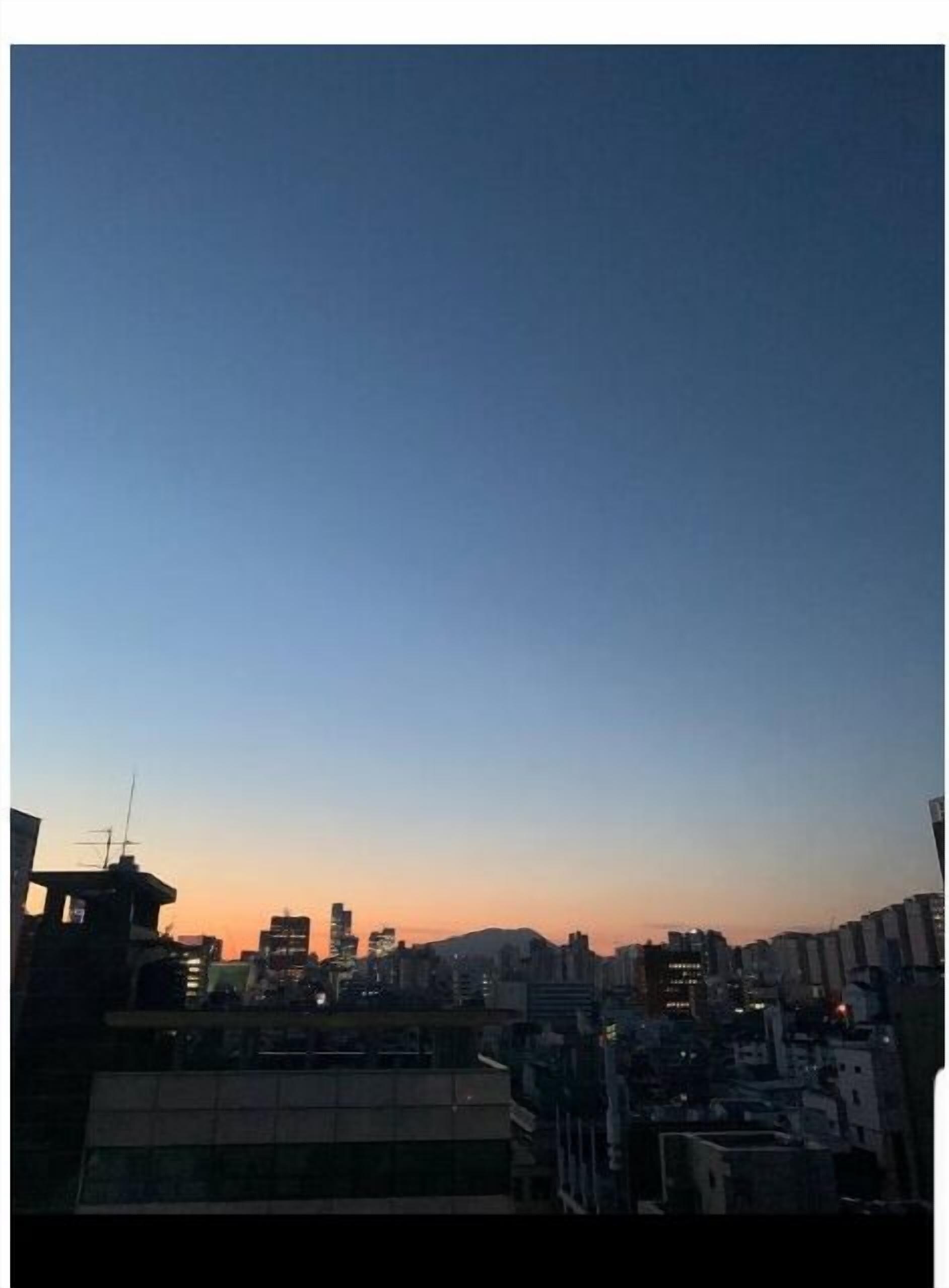 Eine Stadtlandschaft im Abendrot, Gebäude silhouettiert vor blauem Himmel.