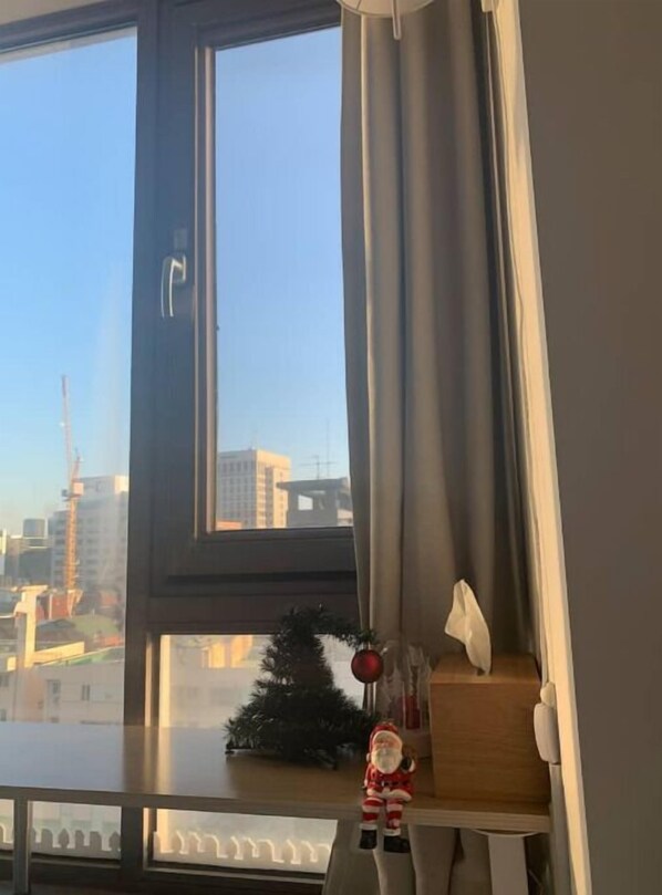 Une pièce avec une grande fenêtre, un petit sapin de Noël et une figurine posée sur le rebord de la fenêtre.