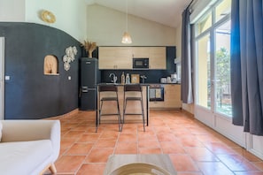 A modern kitchen with a dining area, large windows, and a sofa.