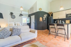 A modern living room with a sofa, chairs, and a kitchen area with a counter and chairs.