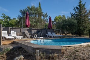 A swimming pool with a wooden deck, white lounge chairs, and red umbrellas. - Holiday Home 'Mûrier' with Mountain View, Wi-Fi and Air Conditioning (Les Vans)
