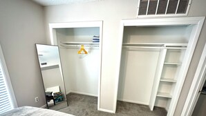 Ein Schlafzimmer mit einem Bett, einem Kleiderschrank mit Platz zum Aufhängen und einem begehbaren Kleiderschrank.