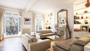 A spacious living room with a fireplace, a large mirror, and a bookshelf filled with books and decorative items.