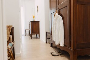 A hallway with a wooden wardrobe, a bench, and a pair of shoes on the floor.