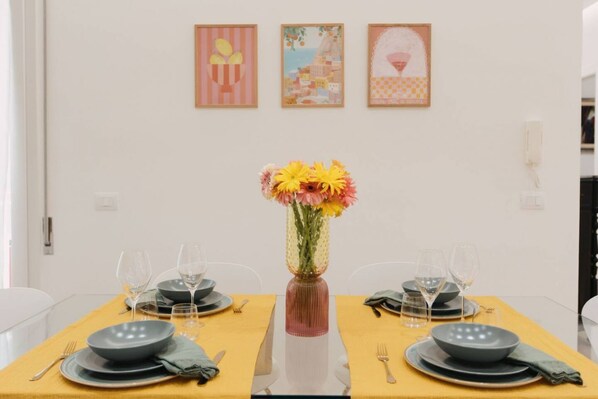 A dining table set with plates, glasses, and a vase with flowers.