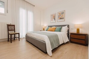 A bedroom with a bed, two bedside tables, a chair, and artwork on the wall.