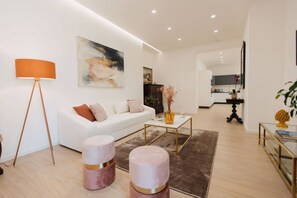 A modern living room with a white sofa, a coffee table, and a lamp.