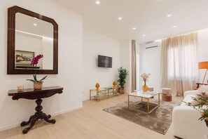 A modern living room with a large mirror, a flat-screen TV, a coffee table, and a sofa.