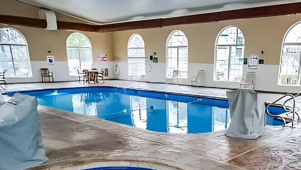 An indoor swimming pool with clear water, a tiled floor, and arched windows. - Charming Studio w/ Pool Access in Branson (Branson)