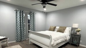 Une chambre à coucher avec un lit, une table de chevet, une lampe et un ventilateur de plafond.