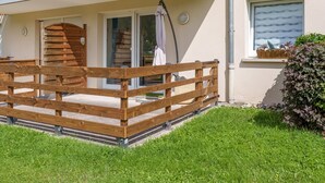 Una terraza de madera con puerta corrediza de vidrio que da a una habitación.